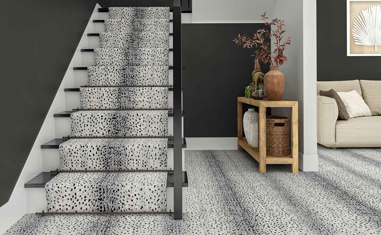 entryway with styled wood entry table, staircase, and gray walls with gray animal print carpet